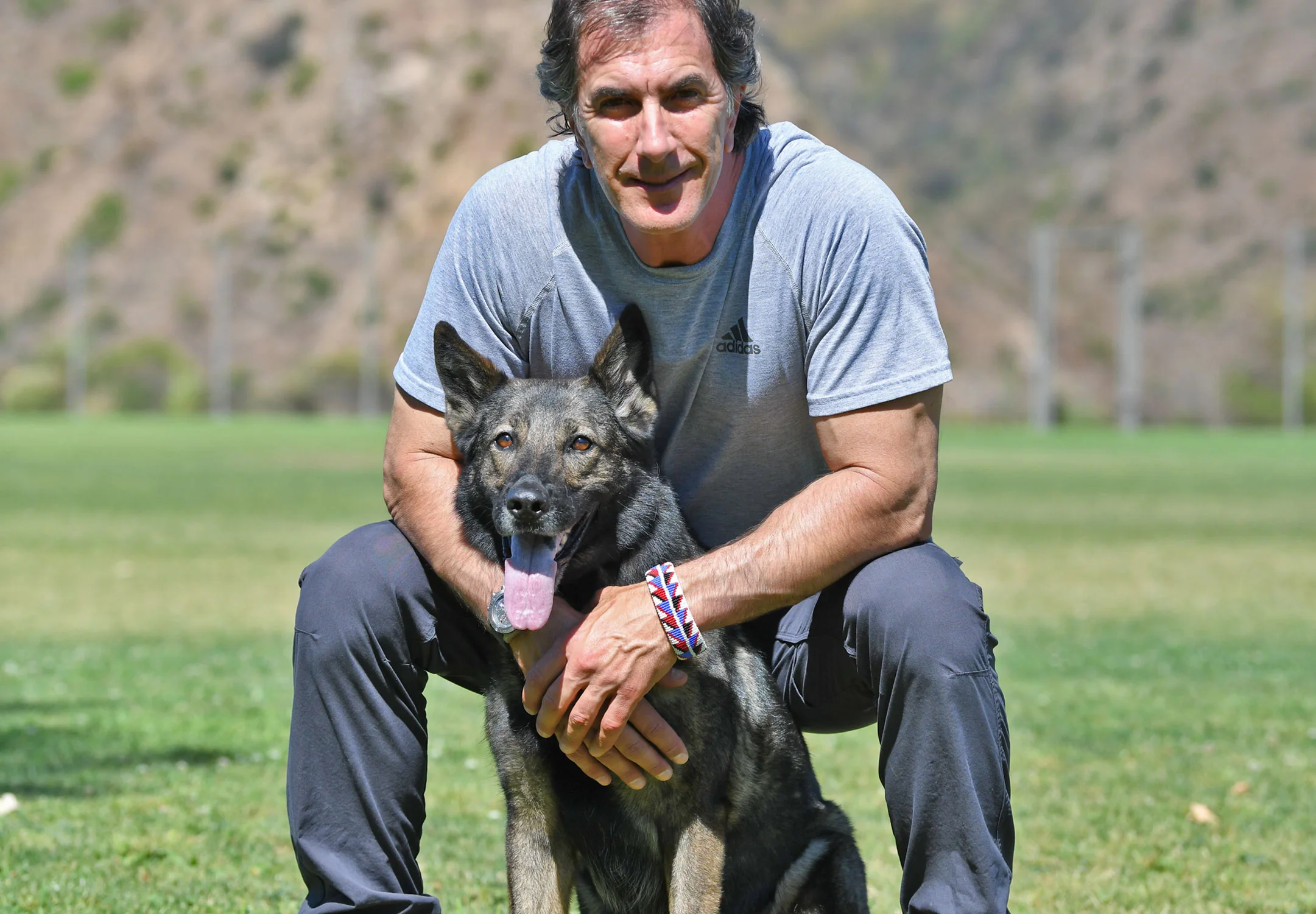 Robert Cabral kneeling with his German Shepherd on a training field